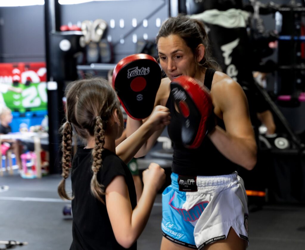 Grace Allison from Dynamis Muay Thai Central Coast coaching a young girl for kids Muay Thai.